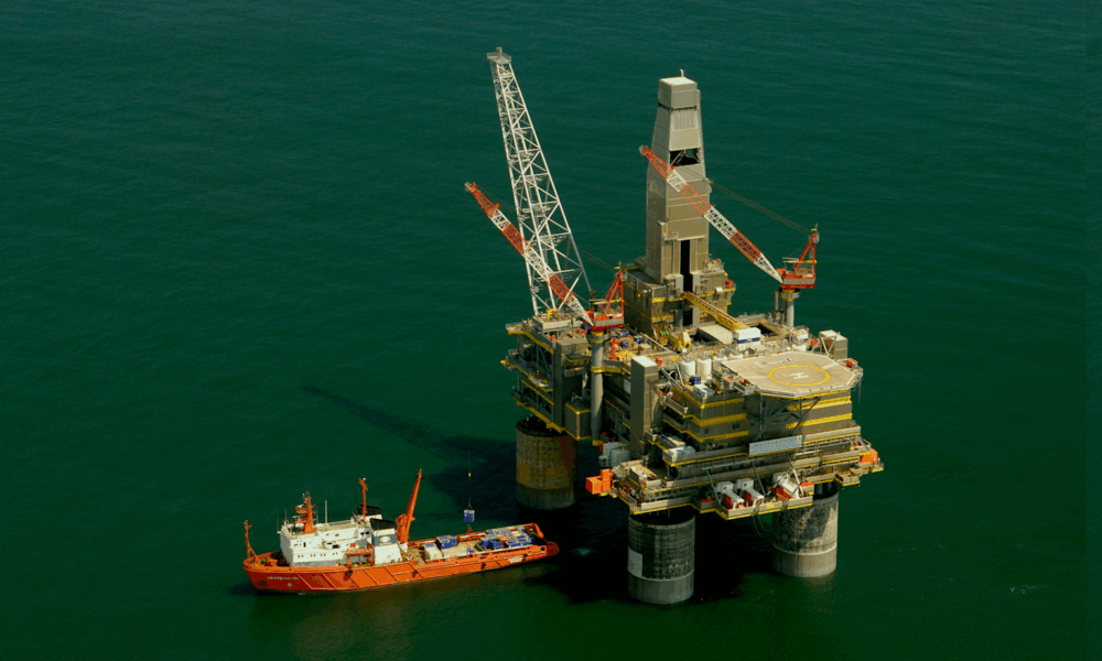 An offshore oil drilling platform with cranes and a supply ship in the ocean